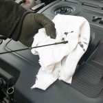 Mécanicien effectuant une vidange d’huile sur une voiture, pour montrer comment faire la vidange de sa voiture.